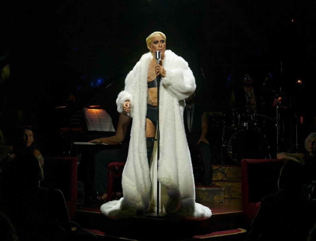 Mario Vaquerizo con abrigo blanco ante el micrófono en el Kit Kat Klub de Cabaret