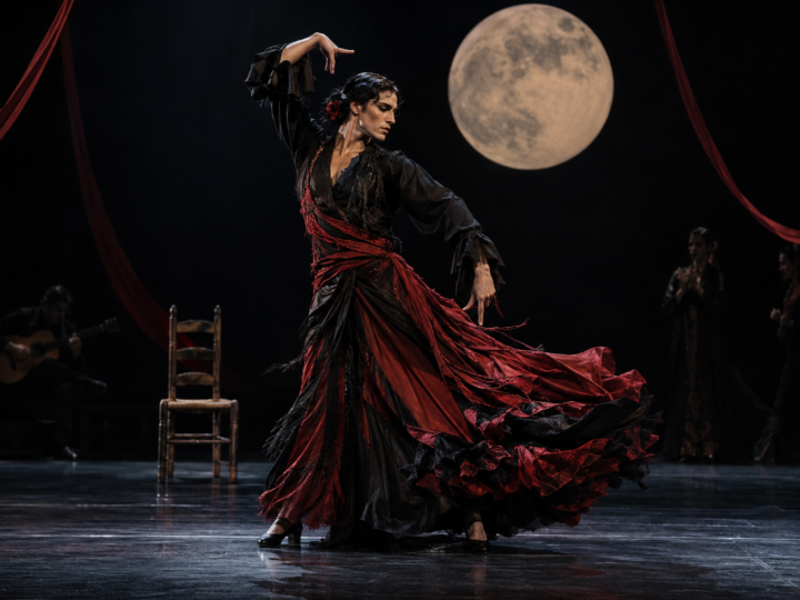 Intérprete de flamenco contemporáneo bajo una luna escénica y telas rojas